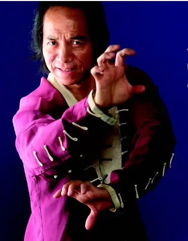 Man in traditional martial arts pose wearing a purple jacket.